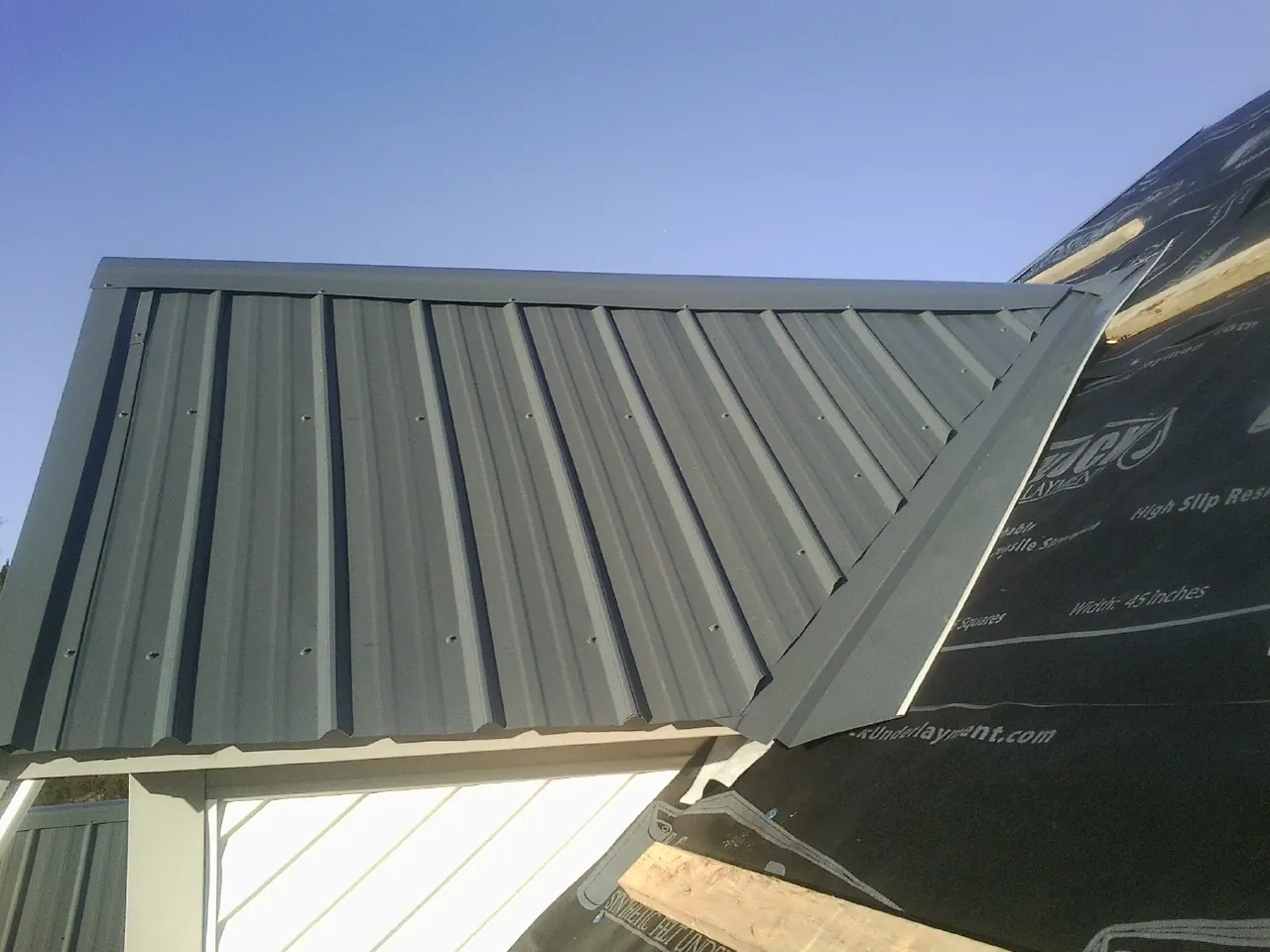 Gray metal roof panels going on over a garage gable in Laurinburg