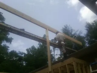 Carpenter setting a ridge beam over a new addition frame — Ice Dam Removal by Roofing Brothers in Laurinburg