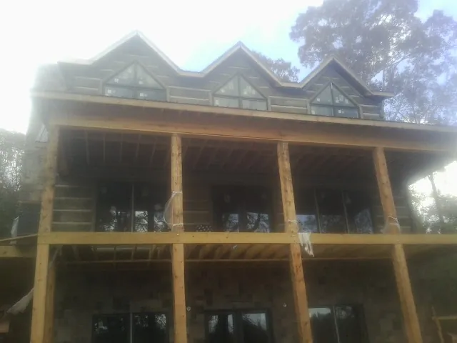 Dormers and porch framing on a large log home under construction — Roof Coating work by our crew in Laurinburg