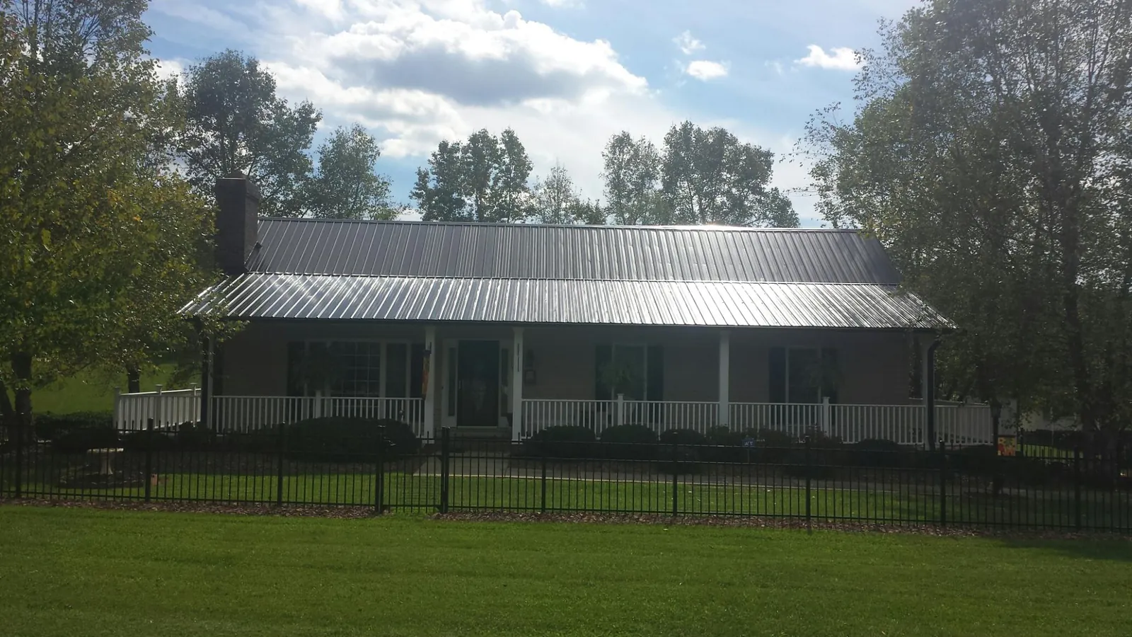 Gray metal roof on a brick ranch with a full width front porch — Gutter Guard Installation work by our crew in Laurinburg