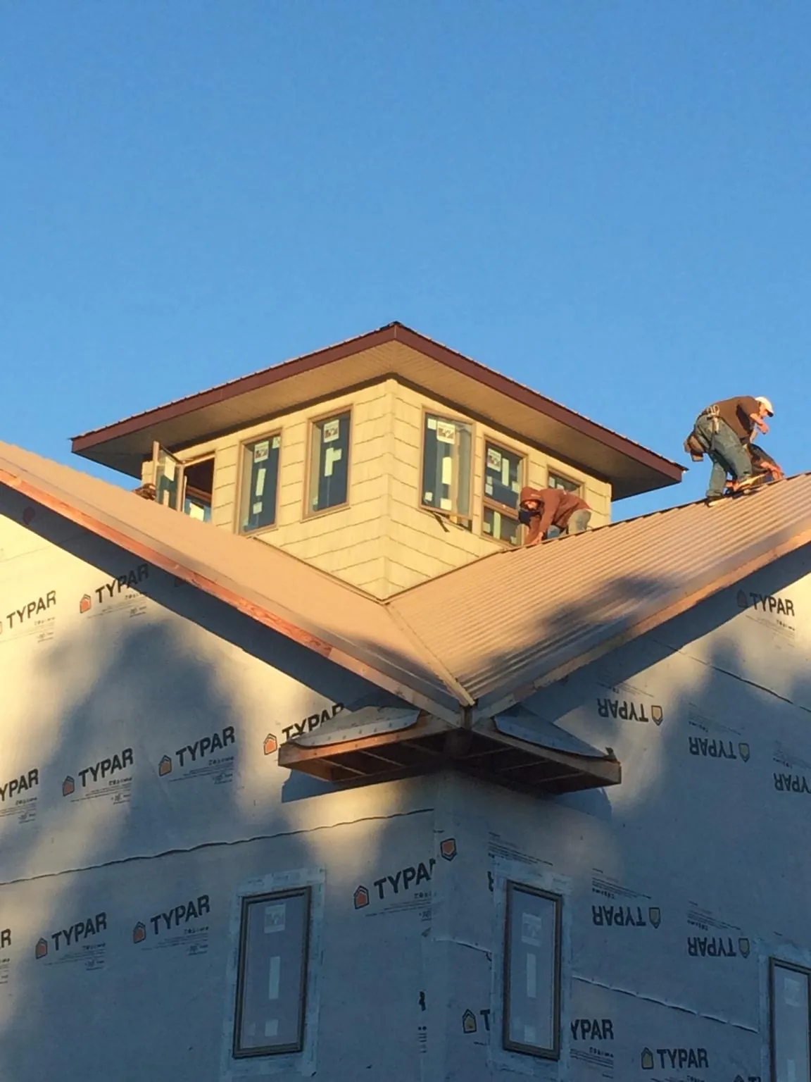 Roofers working around a rooftop cupola on a new metal roof at sunset — Roof Waterproofing in Laurinburg by Roofing Brothers